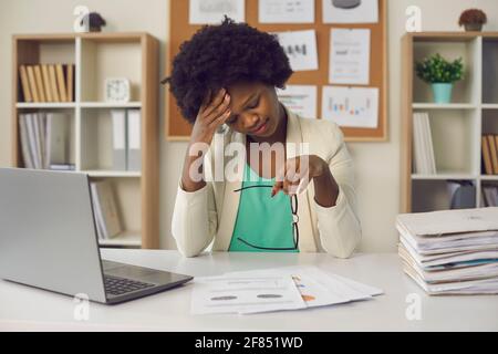 Tired african american businesswoman suffering from headache sit at office table Stock Photo