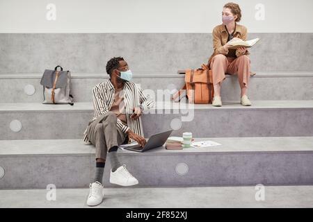 Wide angle portrait of two young students working and relaxing while sitting in graphic college lounge, copy space Stock Photo