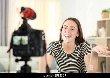 Happy influencer recording video with a dslr camera talking at camera at home Stock Photo