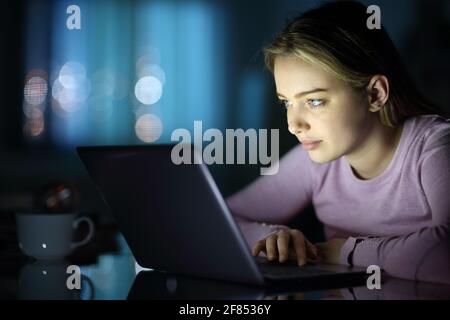 Serious woman using laptop searching online content in the night at home Stock Photo