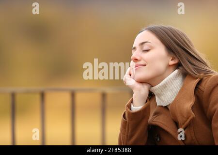 Happy woman relaxing with closed eyes sitting in a balcony in winter Stock Photo