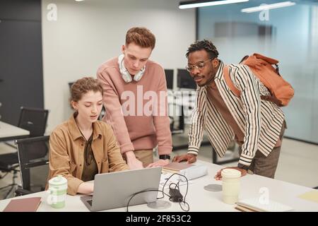 Group of young students using laptop together while working on school project in modern college, copy space Stock Photo