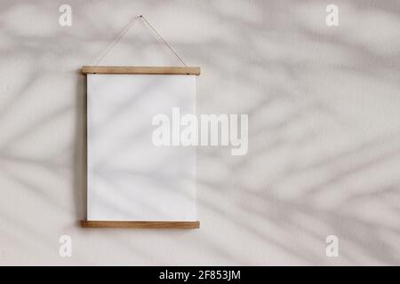 Blank wooden picture frame hanging on beige wall. Empty poster mockup for art display in sunlight. Minimal interior design.Palm leaves shadow overlay Stock Photo