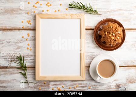 White wooden frame mockup with cup of coffee and cake on white wooden background. Blank, top view, flat lay, still life. Stock Photo