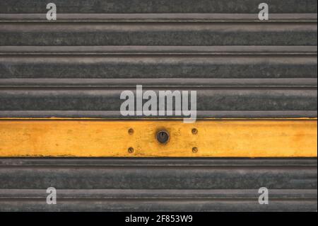 detail of a metal shutter of a garage with yellow stripe Stock Photo