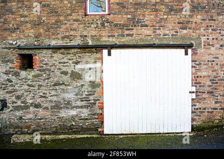 Wooden sliding door on a traditional Irish brick built barn in an old farm. Stock Photo