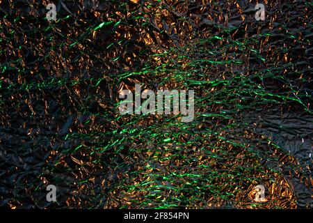 Abstract gold and green aluminum wrinkled foil background texture reflecting green and golden yellow light Stock Photo