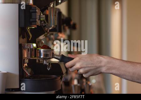 Side view closeup of male hand operating coffee machine while making fresh coffee in cafe, copy space Stock Photo