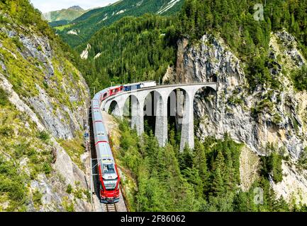 Passenger train crossing the Landwasser Viaduct in Switzerland Stock Photo