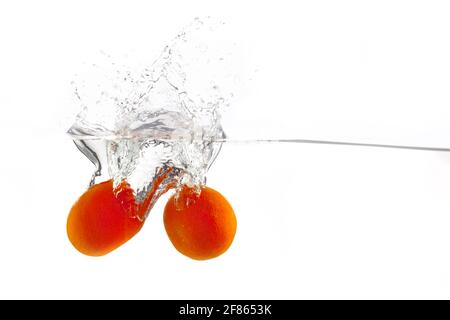 two tangerines falls into the water on a white background, isolate, place under the text Stock Photo