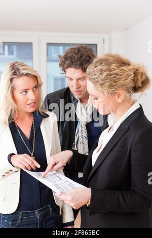 Young realtor explain lease agreement or purchase contract with floor layout to couple in an apartment, close-up Stock Photo