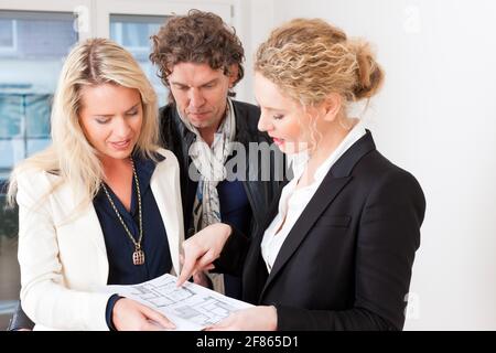 Young realtor explain lease agreement or purchase contract with floor layout to couple in an apartment, close-up Stock Photo