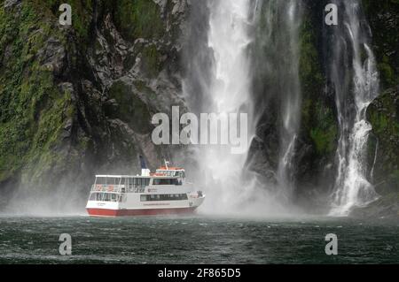 Tourist Boat on Milford Sound, New Zealand, 28 March, 2021 -  A tourist cruise boat run by South Discoveries tours named the Lady Bowen takes tourists underneath the Stirling Falls in Milford Sound in the Fiordland region of New Zealand's south western region. Stirling Falls is 151m and is three times the height of Niagara Falls. Credit: Rob Taggart/Alamy Stock Photo