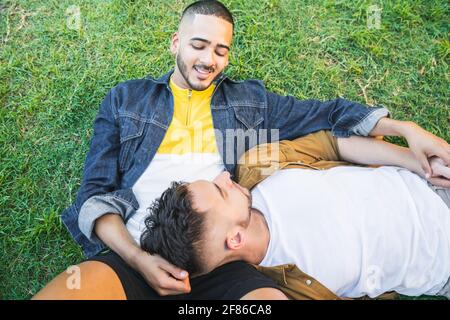 Gay couple laying down on the grass at the park. Stock Photo