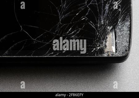 Closeup of a broken smartphone with cracked screen isolated on a gray background. Stock Photo
