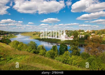 View on ancient white-stone Convent of the Dormition built in 16 century on Volga River bank with reflection in water. Staritsa, Tverskoy region, Russ Stock Photo