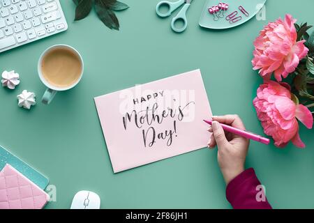 Mothers day greeting card design. Text Happy Mother's day. ink peony flowers on faded mint green background with paper confetti. Coffee, keyboard, flo Stock Photo
