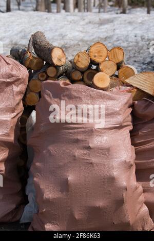 Recently cut birch logs stacked on top of pink plastic sacks Stock Photo