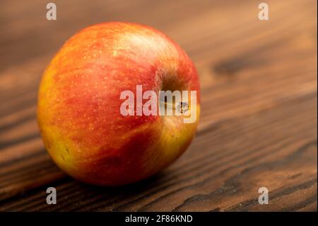 A fresh red apple on a rustic wooden table. Close-up selective focus. Stock Photo