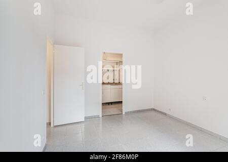 Empty white room connected with small kitchen. Typical apartment for rent in Barcelona. Stock Photo