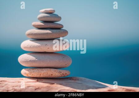 Pyramid stones on the seashore on a sunny day on the blue sea background. Happy holidays. Pebble beach, calm sea, travel destination. Concept of happy