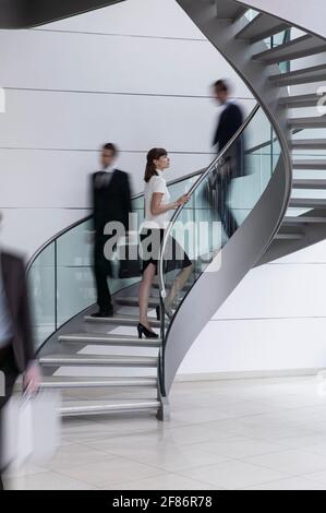 Young businesswoman ascending spiral staircase in office Stock Photo