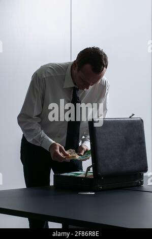 Businessman counting money at briefcase in office Stock Photo