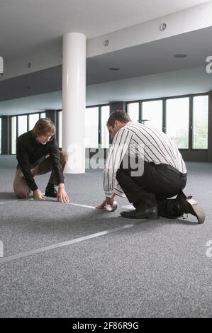 Businessmen measuring and marking floor in new office Stock Photo