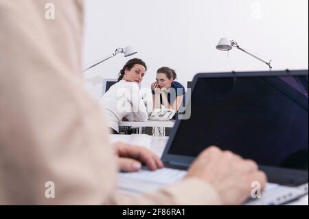 Businesswomen gossiping about colleague in office Stock Photo