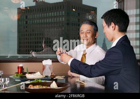Japanese businessmen drinking with lunch in highrise restaurant Stock Photo