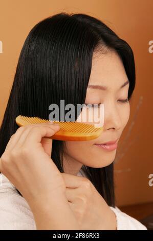 Serene beautiful young woman combing hair Stock Photo