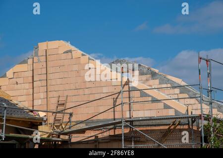House construction attic becomes brickwork with blue sky and scaffolding Stock Photo