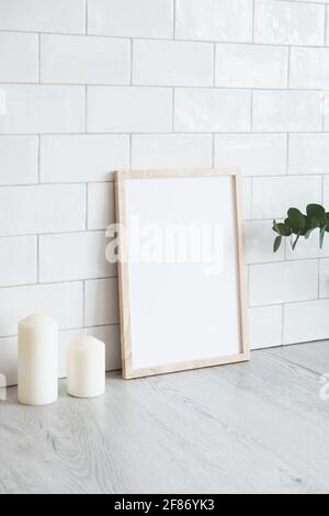 Empty poster frame in cozy interior. Frame mockup. Brick tiles wall on background. Scandinavian, nordic style. Stock Photo