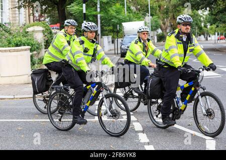 British Metropolitan Police officers on bicycles in high viz jackets, Notthing Hill, London, UK