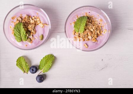 Bowls of berries yogurt with granola and oats for healthy breakfast on a rustic white table background. Top view. Stock Photo