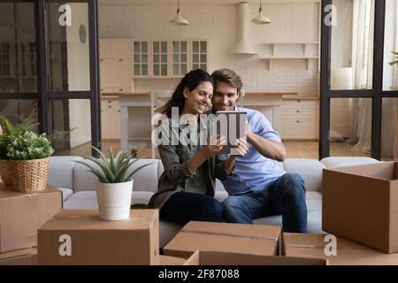 Happy couple using tablet, choosing moving service for relocation Stock Photo