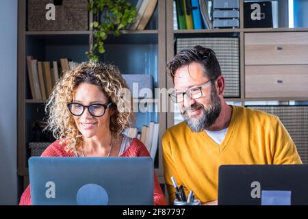 People at work at home with internet connection and computer laptop in couple - man and woman working together - modern man and woman online job activ Stock Photo