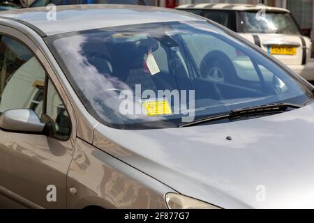 A Car parked illegally on a street with a parking ticket stuck to the windshield Stock Photo
