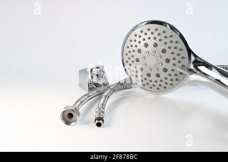 Shower head, wall mount and flexible water connections on a light background. Plumbing accessories. Stock Photo