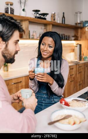 Smiley black woman and her boyfriend having delicious breakfast in the kitchen at home. Stock Photo