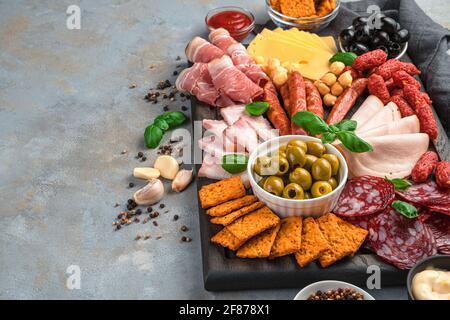 Charcuterie board with different types of sausage and cheese on a gray background with spices and garlic. Side view with copy space. Stock Photo