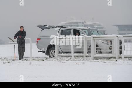 Epsom Downs, England. 12 April, 2021. Workers from the Jockey Club prepare Epsom Racecourse for the spring meeting in the snow at Epsom Downs. Credit: Nigel Bramley Credit: Nigel Bramley/Alamy Live News Stock Photo