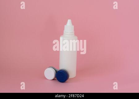 Contact lens case and bottle of solution on pink background Stock Photo