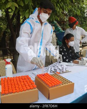 New Delhi, India. 12th Apr, 2021. A healthcare worker wearing a personal protective equipment (PPE) places a mouth swab sample vial into a box after Covid-19 Reverse Transcription Polymerase Chain Reaction (RT-PCR) test at the road side testing centre Wazzirpur industrial area in New Delhi. India registered 168,912 new Covid-19 cases, the highest single-day spike and 904 deaths in the last 24 hours. (Photo by Naveen Sharma/SOPA Images/Sipa USA) Credit: Sipa USA/Alamy Live News Stock Photo