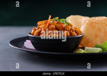 Indian breakfast  Poori with chickpea chana masala curry,tasty indian dish made using all purpose wheat flour which is arranged in a black plate with Stock Photo