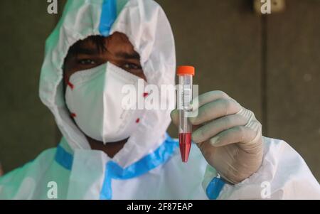 New Delhi, India. 12th Apr, 2021. A healthcare worker wearing a personal protective equipment (PPE) holds a mouth swab sample vial after Covid-19 Reverse Transcription Polymerase Chain Reaction (RT-PCR) test at the road side testing centre Wazzirpur industrial area in New Delhi. India registered 168,912 new Covid-19 cases, the highest single-day spike and 904 deaths in the last 24 hours. Credit: SOPA Images Limited/Alamy Live News Stock Photo