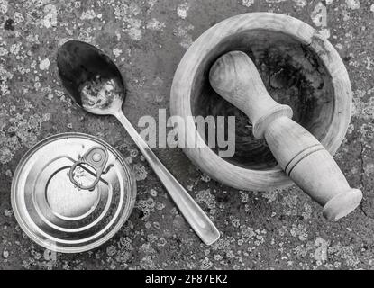 Top view of a can of packaged food, a wooden mortar and a metal spoon on a spotted background, in black and white Stock Photo
