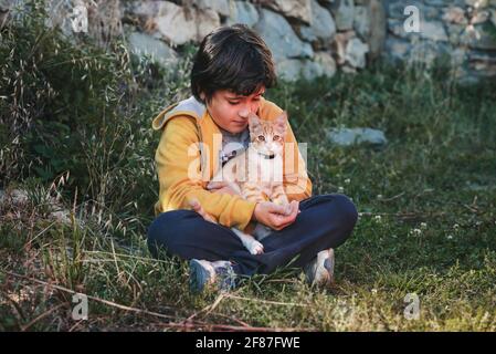kid sitting on the grass with his kitten outdoor Stock Photo