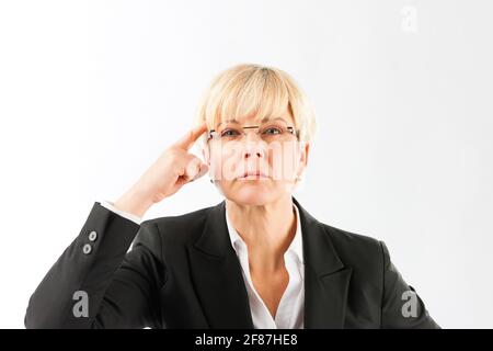 An angry mature businesswoman pointing her finger on forehead over white background Stock Photo