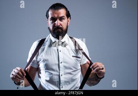 Handsome young businessman pulling his suspenders. Attractive